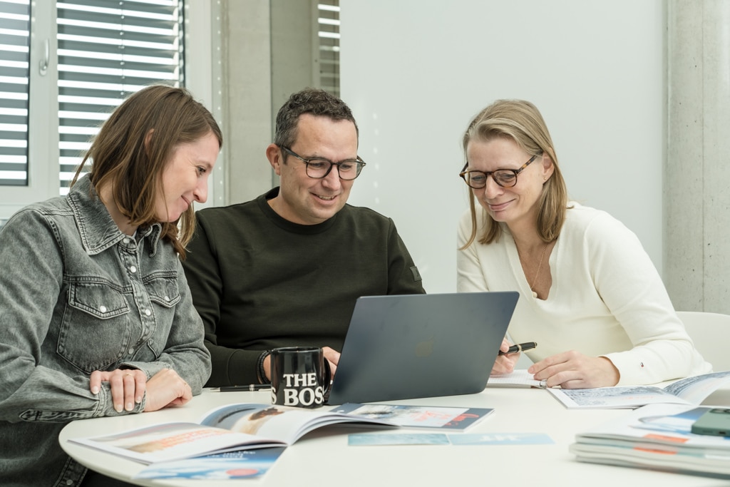 Sascha Nitsche sitzend am Tisch mit Computer und zwei Mitarbeiterinnen